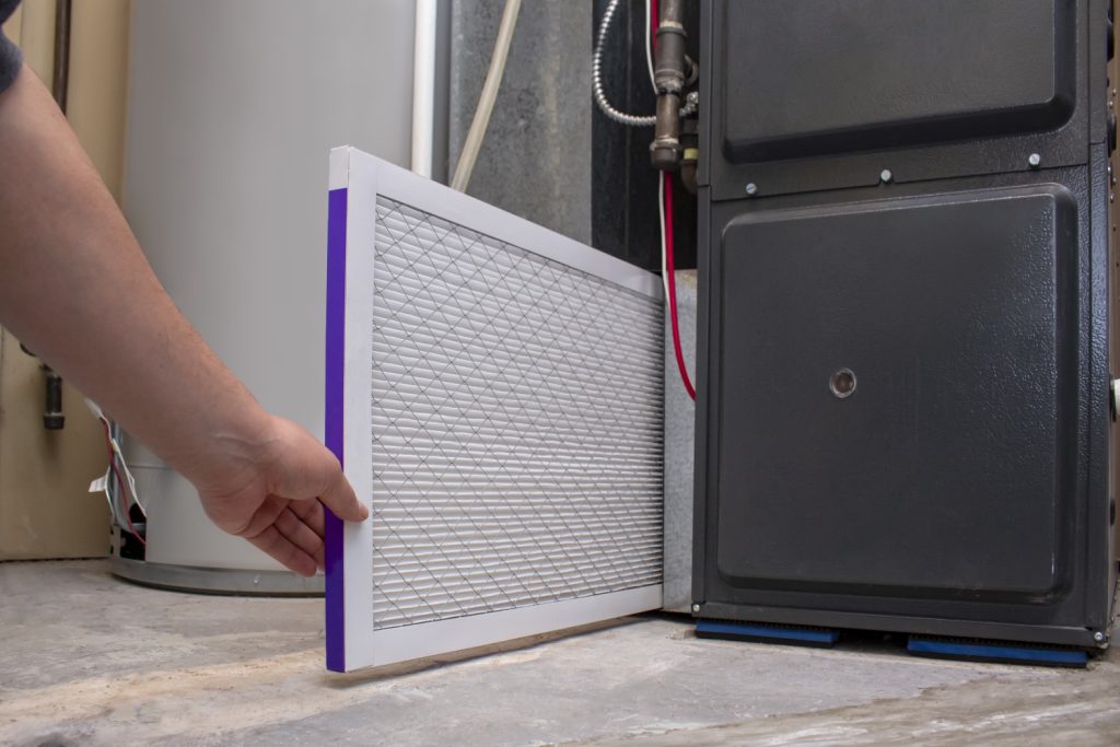 A Person Changing An Clean Air Filter On A High Efficiency Furna